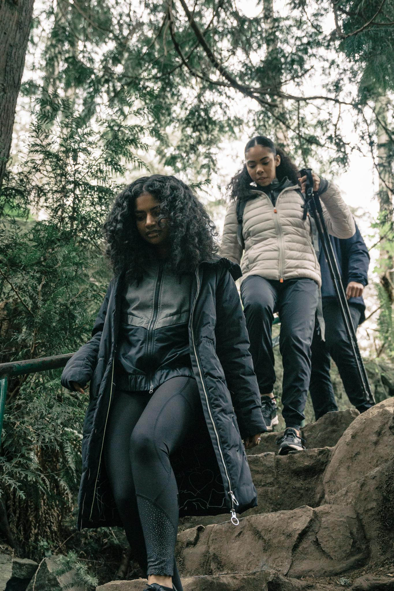 Three women hiking down a stone path in the forest, enjoying outdoor adventure.